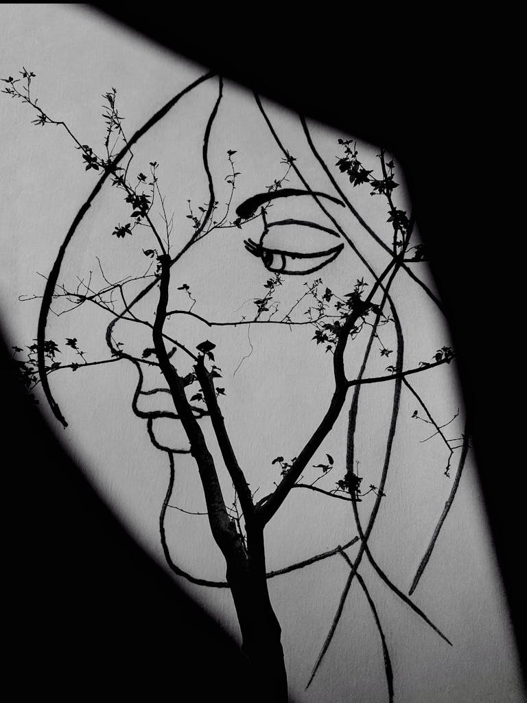 Grayscale Photo of Tree Branches Forming a Woman's Face